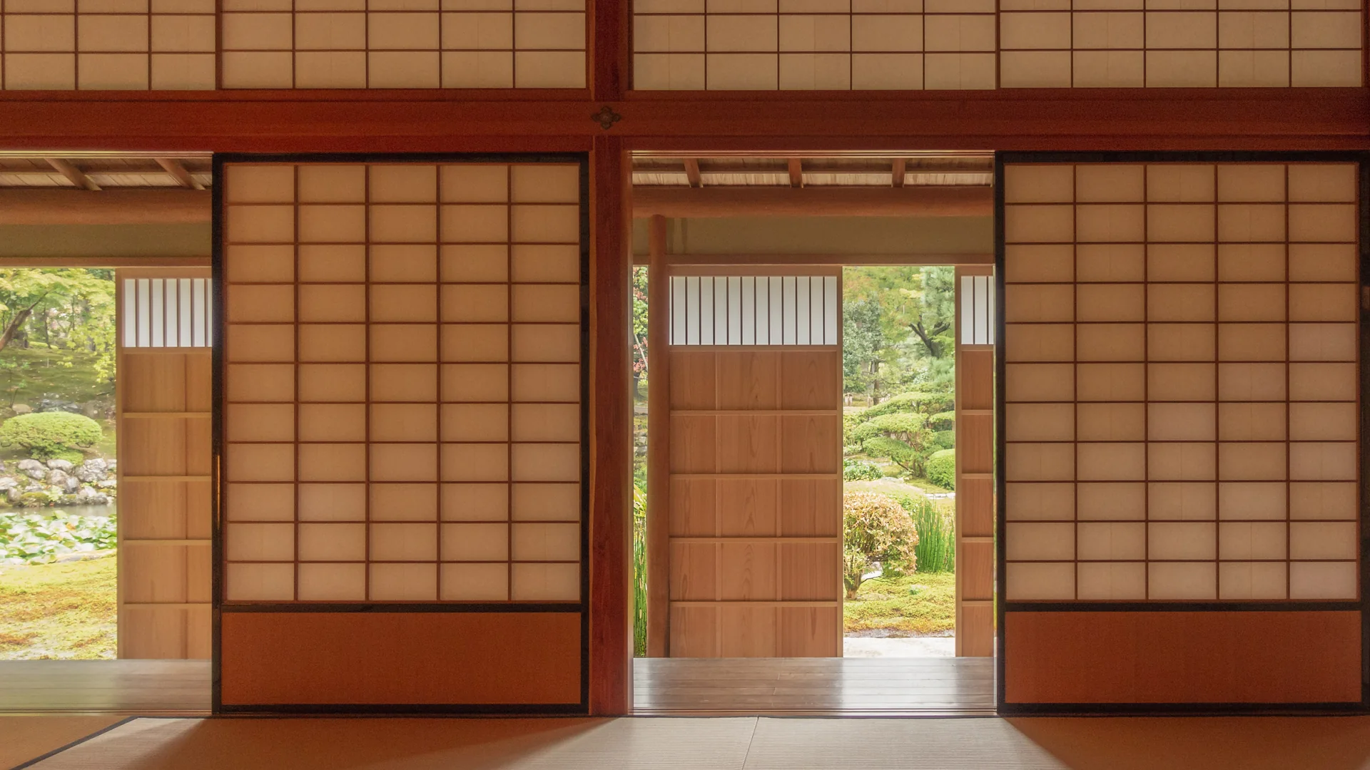 A tatami tea room with sliding paper screens open onto a garden of pines and moss; a general photograph of a tea room in Kanazawa, not of this tea house